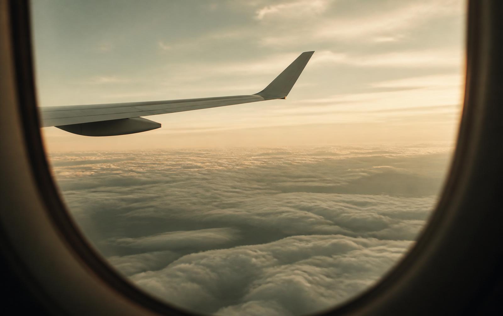 Vista serena desde la ventana de un avión sobre un mar de nubes al atardecer